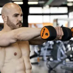 Uomo con manubri in palestra, parte di una scheda multifrequenza 4 giorni.