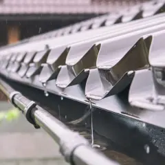 Deszcz spływa po metalowym dachu garażu, a mocowanie rynny do garażu blaszanego skutecznie odprowadza wodę.