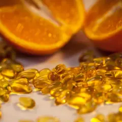 Orangenscheiben und Kiwi neben vielen gelben Kapseln. Die Wirkung von hochdosiertem Vitamin C für die Gesundheit.