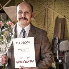 Adam Woronowicz w roli Huberta Myślińskiego z dyplomem i kwiatami. Scena z jednego z jego filmów.