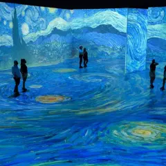 Visitors stand immersed in a swirling, starry landscape, a breathtaking projection of a Van Gogh painting.