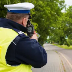 Policjant mierzy prędkość. Kierowco, uważaj na przekroczenie prędkości o 20 w terenie zabudowanym, bo możesz dostać mandat.