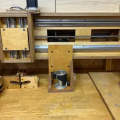 Domowa frezarka CNC DIY z drewna i metalowych prowadnic. Widać silnik krokowy, wrzeciono z frezarką ręczną i mechanizm śrubowy.