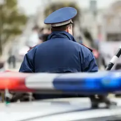 Policjant w mundurze stoi przy radiowozie. Zastanawiasz się, ile zarabia policja kryminalna?