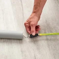 Dłoń przytrzymuje końcówkę kabla, przygotowując ją do przeciągnięcia przez peszel.