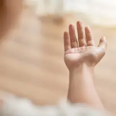 Dłoń wyciągnięta w górę, lekko drżąca, jakby w geście prośby lub nadziei.