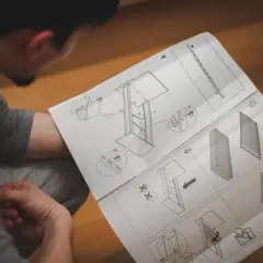 Mężczyzna studiuje schemat, ucząc się, jak napisać instrukcję obsługi urządzenia. Ilustracje pokazują kolejne kroki montażu.