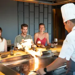 Chef prepara teppanyaki que es una experiencia culinaria interactiva. Los comensales disfrutan del espectáculo de fuego y la comida.
