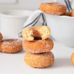 Rosquillas caseras de toda la vida, doradas y espolvoreadas con azúcar, apiladas y esparcidas. Un placer que evoca recuerdos.