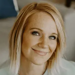 Adrienne Camp lächelt warm, ihre Sommersprossen und blauen Augen strahlen.
