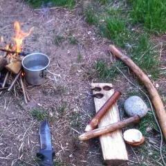 Un cuchillo, un cazo y leña para prender fuego. Preparativos para una noche al aire libre.