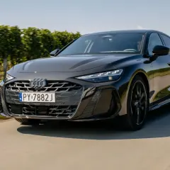 Eleganckie, czarne Audi A6 C9 w ruchu, z grillem i reflektorami w pełnej krasie, na tle zielonych winnic.