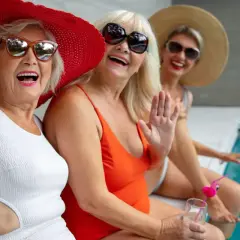 Trzy uśmiechnięte kobiety w strojach kąpielowych i kapeluszach robią sobie selfie przy basenie. To dowód, że nigdy nie jest za późno, by zacząć szukać i jak znaleźć przyjaciela.