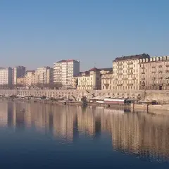 I **murazzi** di Torino si specchiano nel fiume, con palazzi storici e moderni che si affacciano sulla riva.