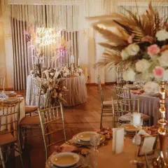 Elegancka sala weselna z neonem "All you need is love". Złote krzesła, pudrowo-różowe obrusy i bujne kwiaty. Zastanawiasz się, ile kosztuje udekorowanie sali weselnej w takim stylu?