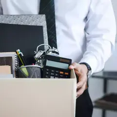 Un étudiant quitte son emploi, portant une boîte remplie d'objets de bureau, symbolisant une lettre de démission contrat étudiant sans préavis.