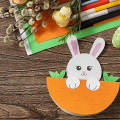 Uroczy króliczek w marchewce, idealny pomysł na kartkę wielkanocną 3d jak zrobić. Materiały do rękodzieła na drewnianym tle.