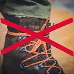 A red X crosses over a brown hiking boot with orange laces. The question "why are boot laces so long?" is implied.