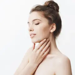 Delikatna skóra szyi, jak po zabiegu z kwasem glikolowym czy salicylowym. Kobieta dotyka swojej gładkiej szyi.
