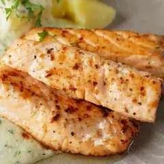 Zwei saftige Lachsfilets, perfekt gebraten, mit cremiger Sauce und Kartoffeln. Ein tolles Gericht für Lachs Rezepte.