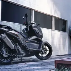 Un hombre apoya su casco en una moto moderna, lista para la aventura. La ficha técnica de esta moto promete potencia y estilo.
