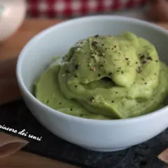 Una cremosa salsa avocado, cosparsa di pepe nero, in una ciotola bianca. Perfetta per accompagnare pasta o come dip.