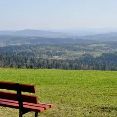 Ławka na tle malowniczego krajobrazu z lasami i pagórkami. Widok z szybowiska Bezmiechowa zapiera dech w piersiach.