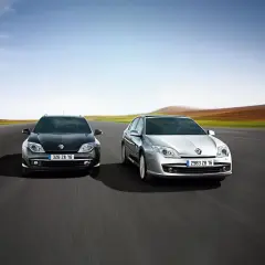 Dwa modele Renault Laguna 3, czarny i srebrny, pędzą po pustej drodze na tle rozmytego krajobrazu.