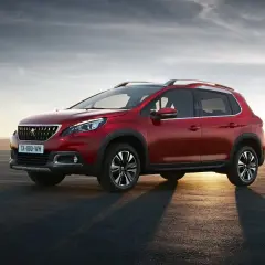 Czerwony Peugeot 2008 na tle zachodzącego słońca. Wiele osób szuka peugeot 2008 opinie przed zakupem.