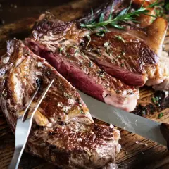 Saftigt bavette steak, perfekt stekt med rosmarin och havssalt, redo att skäras upp på en rustik träskärbräda.