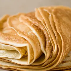 Pile de crêpes dorées, parfaites pour une recette crêpe sans beurre. Elles sont fines et légères, prêtes à être garnies.