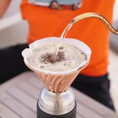 Heißes Wasser fließt aus einer Kupferkanne in einen Filter, um köstlichen Kaffee zu machen.