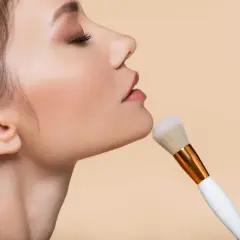 Primo piano del viso di una donna con pennello da trucco. La cipria traslucida dona un finish naturale e opacizzante, il suo significato è perfezione.