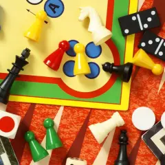 Bunte Spielfiguren, Würfel, Dominosteine und Schachfiguren liegen verstreut. Eine bunte Mischung bekannter Brettspiele für endlosen Spielspaß.