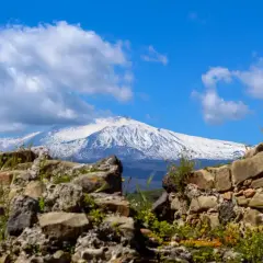 Rovine antiche incorniciano la maestosa vista dell'Etna innevato, un paesaggio iconico di Taormina.