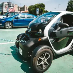 Mały, elektryczny pojazd, którym można jeździć bez prawa jazdy, ładuje się obok innych samochodów elektrycznych.
