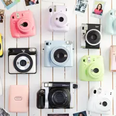 Kolekcja kolorowych aparatów do fotografii natychmiastowej Instax, ułożonych na białym tle.