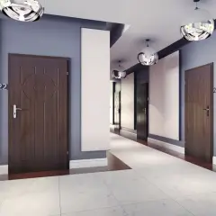 Nowoczesny korytarz w bloku z drzwiami, które można wyciszyć. Jasne panele i kule lamp dodają elegancji.