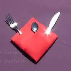 Pliage serviette Noël porte couvert en forme de pochette rouge, avec une fourchette, une cuillère et un couteau.