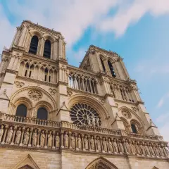 Notre Dame de Paris, une visite inoubliable. La façade majestueuse de la cathédrale se dresse sous un ciel bleu et nuageux.