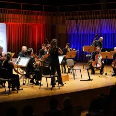Orkiestra symfoniczna gra na scenie. W tle czerwone i niebieskie światła. Wspaniały radom koncert dzisiaj!