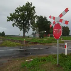 Wielotorowy przejazd kolejowy z czerwonym znakiem STOP i rogatkami.