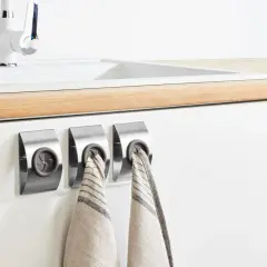 Colgadores de trapos modernos de acero inoxidable junto a un fregadero blanco.