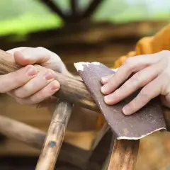 Ręce szlifują drewniany mebel papierem ściernym, przygotowując go do renowacji.