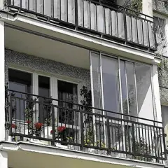 Zabudowany balkon w bloku z przeszklonymi drzwiami i oknami, idealny przykład jak zabudować balkon w bloku, by zyskać dodatkową przestrzeń.