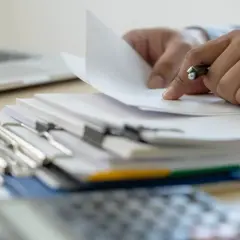 Ręce przeglądają dokumenty, szukając informacji, kiedy można wymeldować członka rodziny.