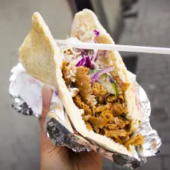 Pyszny kebab w bułce z mięsem, warzywami i sosem. To danie, które swoją popularność zawdzięcza podróżom i wymianie kulturowej, pokazując, skąd pochodzi kebab.