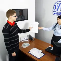 Mężczyzna podaje dokumenty kobiecie przy biurku w biurze PZU.