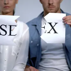 Coppia strappa fogli con lettere "SE" e "X", simboleggiando la fine di una relazione o un'assenza di intimità, forse legata al concetto di asessuale significato.