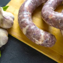 Czosnek i surowa kiełbasa na desce. Ile czosnku na 10 kg mięsa do kiełbasy?